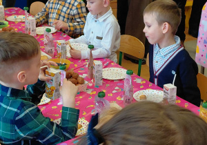 Dzieci spożywają słodki poczęstunek.