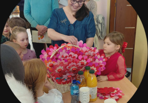 Dzieci z nauczycielką rozdają upominki.