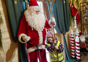 Dziewczynka stoi obok świętego Mikołaja.