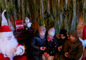 Dzieci trzymają w ręku słodycze mikołaje.