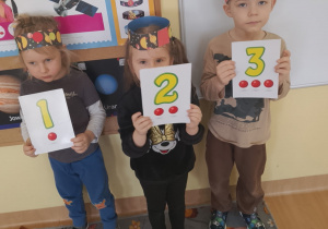 Dzieci trzymają obrazki z cyframi 1,2,3.