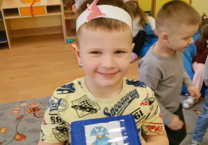 Chłopiec trzyma kostkę z obrazkami dinozaurów.